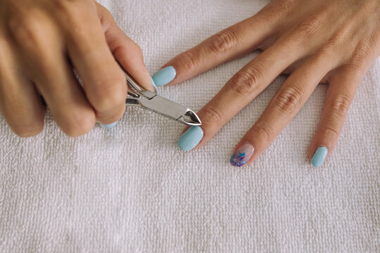 From above of crop unrecognizable young female cutting cuticles with nipper in beauty salon