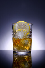 Transparent crystal glass with drink, slice of lemon and ice, advertising photography, selective focus