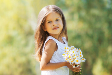 Portrait of happy little girl child with bouquet of wildflowers in sunny summer day