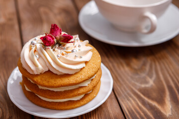 Sponge cake with cream, decorated with small flowers and a cup of tea.
