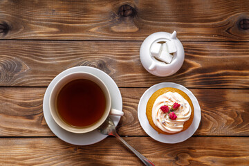 Obraz premium Sponge cake with cream, decorated with small flowers and a cup of tea.