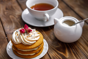 Sponge cake with cream, decorated with small flowers and a cup of tea.