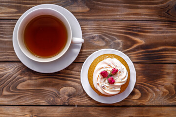 Sponge cake with cream, decorated with small flowers and a cup of tea.