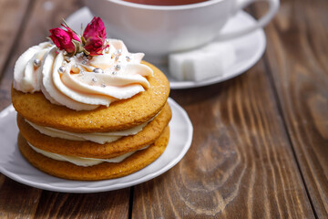 Sponge cake with cream, decorated with small flowers and a cup of tea.