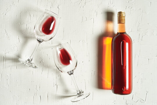 Top view arrangement of fine red wine lying on cracked surface amidst wineglasses