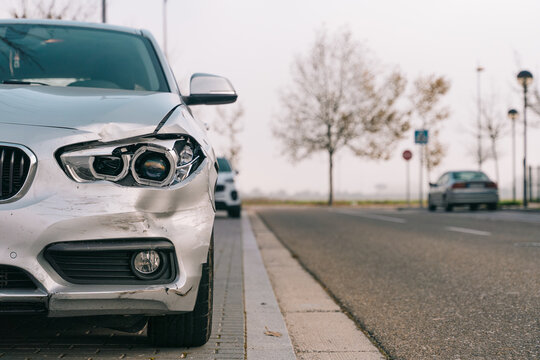 Broken headlight and damaged bumper of modern stylish car parked at roadside after accident on sunny day