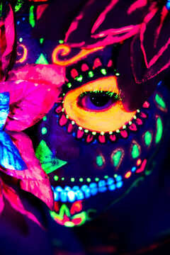 Anonymous female in multicolored masquerade mask with flowers on head looking at camera on Halloween night