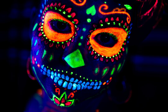 Anonymous female in multicolored masquerade mask with flowers on head looking at camera on Halloween night