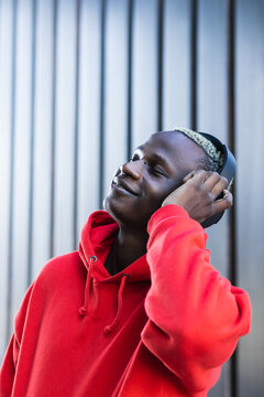 Side View Of Happy Young African American Male Meloman In Trendy Hoodie Enjoying Songs In Wireless Headphones With Closed Eyes