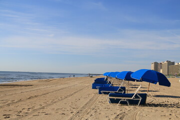 row of blue umbrella beaches lined up in the sandy beaches of Virginia beach in summer