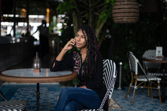 Young attractive afro latina woman speaking on a smartphone in a restaurant