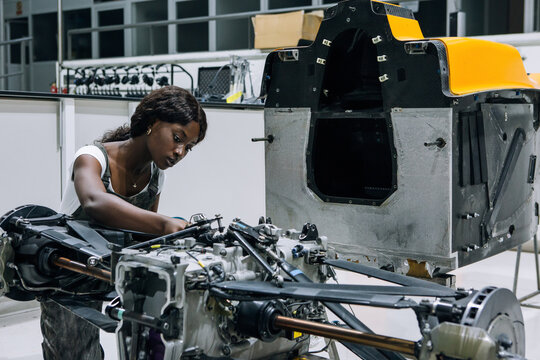 Serious young African American female mechanic assembling custom vehicle in modern repair service center