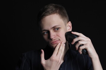 A young man of European appearance shaves his face with