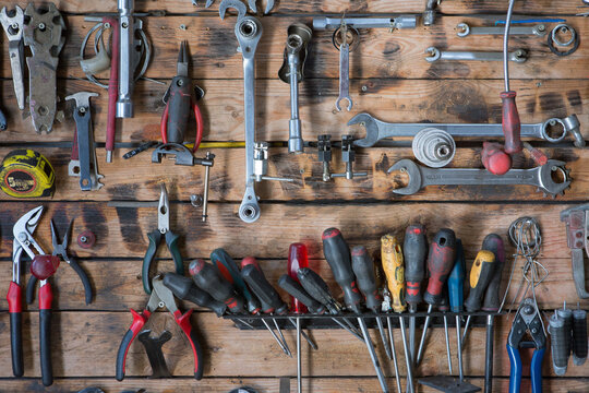 Set of different iron instruments for repairing on lumber wall in modern workshop