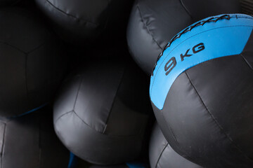 Set of black medicine balls for functional training stacked in rows near wall in modern sports club