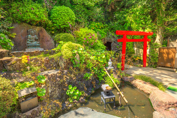 Kamakura, Japan - April 23, 2017: Japanese bamboo fountain in Hase-Dera garden or Hase-kannon and Torii gate or Shinto gate in front of Benten-kutsu cave entrance. Hasedera Temple is popular landmark
