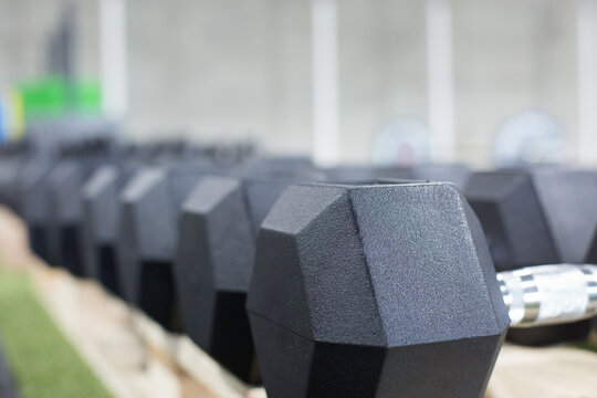 Row of heavy metal dumbbells for intense functional training arranged together in modern sports club