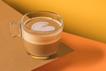 Glass cup of fresh hot aromatic cappuccino with latte art in shape of heart served on table