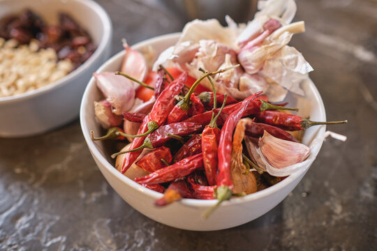 From above bowl with dried chili peppers and cloves of aromatic garlic placed on table in kitchen at home