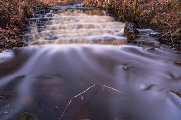 waterfall in several stages and fallen leaves
