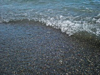Coastal wave on the background of sea pebbles