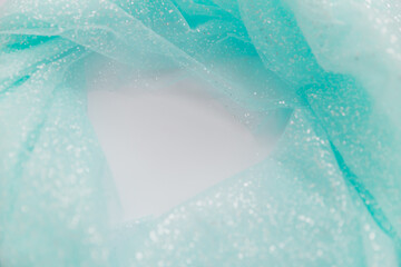 Close up picture of blue mint tulle fabric with glitter on the white background. Abstract wallpaper for the fashion industry with copy space for text. Round shape for text, flat lay.