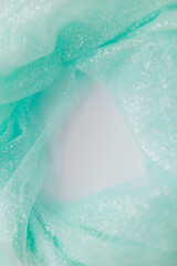 Vertical close up picture of mint tulle fabric with glitter on the white background. Round shape for text, flat lay. Abstract wallpaper for the fashion industry with copy space for text.