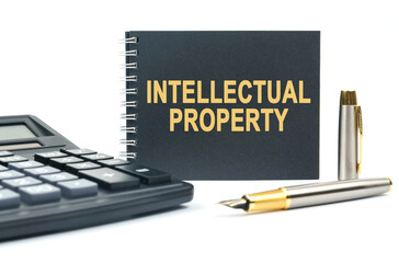 On a white background, there is a calculator, a pen and a black notebook with the inscription - INTELLECTUAL PROPERTY