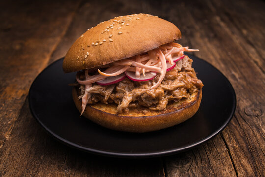 Closeup of yummy hamburger with juicy pulled pork and vegetables in toasted bun