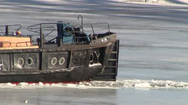A small river boat icebreaker breaks the ice on the Sozh River in the spring on a sunny day.