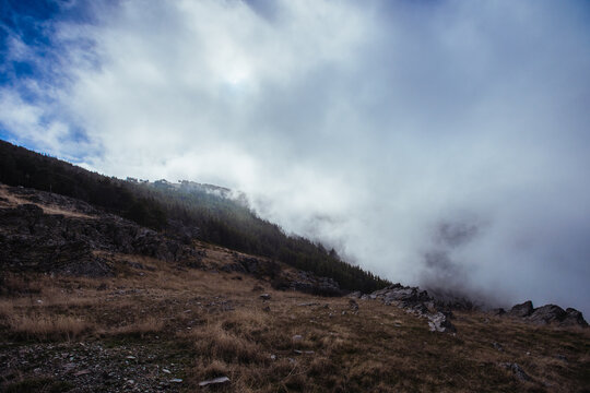 Picturesque view of high ridges with haze under glowing blue sky with clouds in sunlight