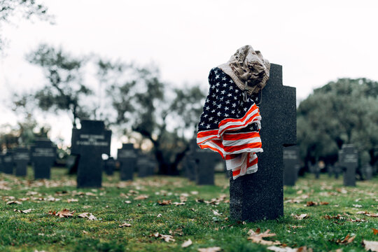 National American flag and army flag placed on gravestone in military cemetery on early autumn day