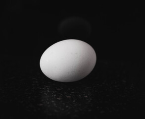 The egg is white, against a black background. Selective focus.