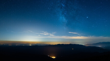 Picturesque view of majestic mount silhouettes under colorful starry sky with clouds at dusk in Spain