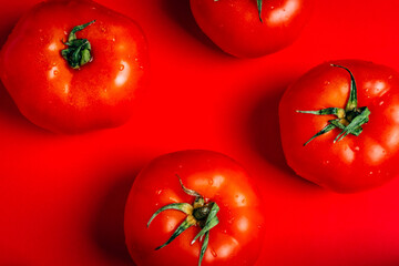 Overhead shot of four ripe red tomatoes on a red background. Vegan concept. Healthy food.