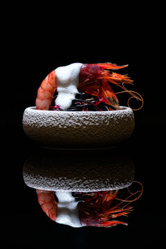 Delicious dish with prawn and sea urchin served in bowl with white sauce and placed on mirrored table in molecular gastronomy restaurant