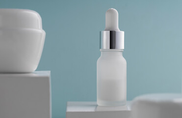 Pipet bottle between cream containers on blue background