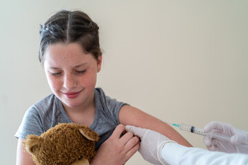 Unrecognizable crop nurse making injection of vaccine from coronavirus for child sitting in medical room with closed eyes