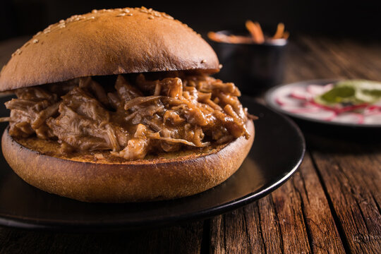 Closeup of yummy hamburger with juicy pulled pork and vegetables in toasted bun