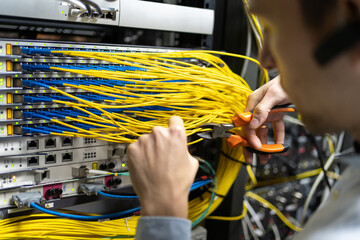 Crop male technician with wire cutters working with electronic system of server room