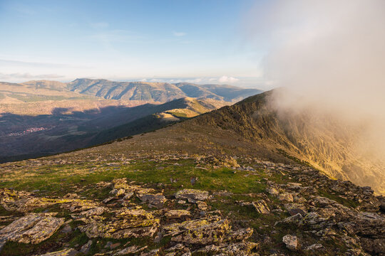 Picturesque view of high ridges with haze under glowing blue sky with clouds in sunlight