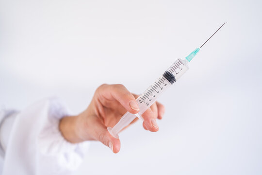 Cropped unrecognizable female hand holding vaccine from coronavirus in syringe in medical room of hospital