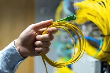 From below of crop anonymous man putting electronic cable in data system in communications room