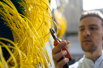 From below blurred male technician with wire cutters working with electronic system of server room
