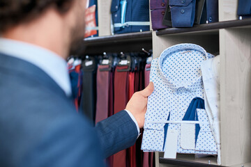 Client picking up stylish shirt in store.