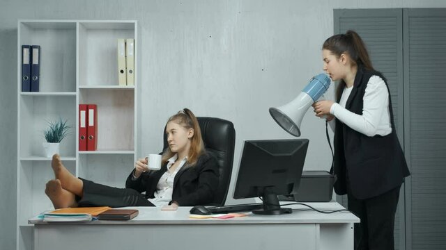 The boss shouts holding a loudspeaker at his lazy subordinate sitting at the table who does not want to work. The employee shows the middle finger