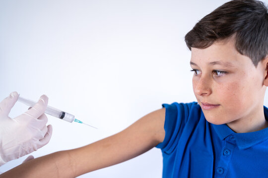Cropped unrecognizable female medic in mask making injection of vaccine from coronavirus for scared boy