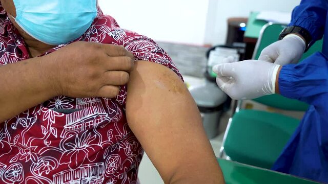 Nurse injects a patient with Covid19 vaccine in Indonesia during pandemic