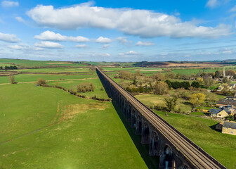 Fototapeta na wymiar An aerial view the village of Harringworth and the railway viaduct as it slices across the Welland Valley on a sunny day in the UK
