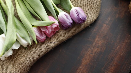 Tulipany na worku jutowym i stole brązowym ciemnym